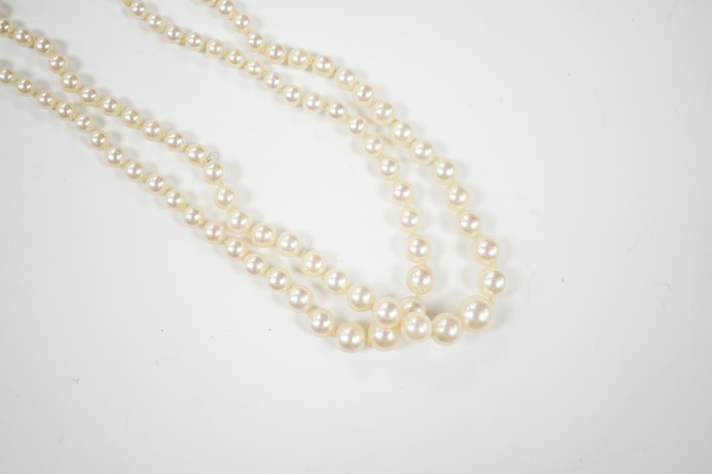 A 1940's French double strand graduated cultured pearl necklace, with diamond set white metal clasp (18ct poincon mark), 46cm.